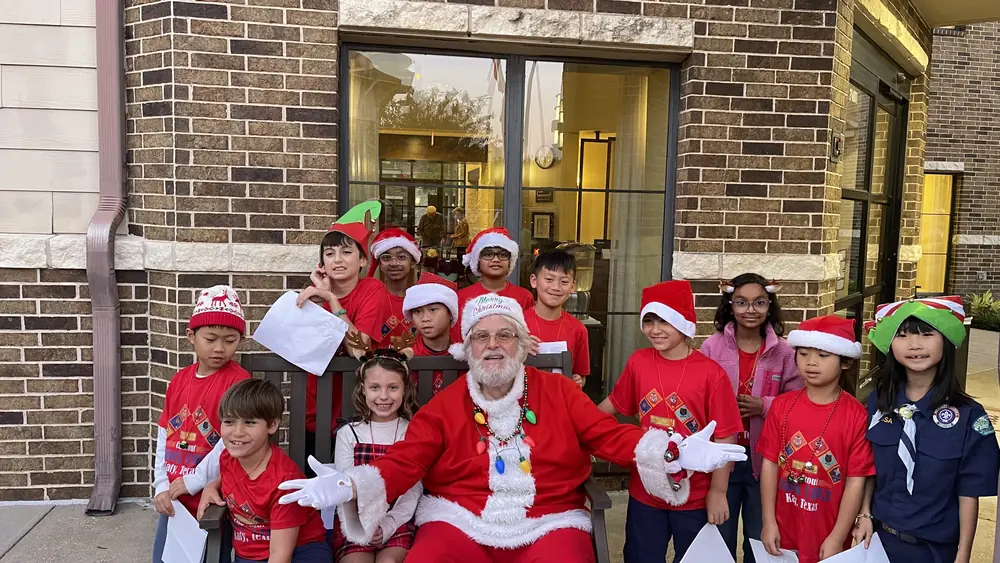 Pack 1103 scouts posing with Santa outside a senior living community