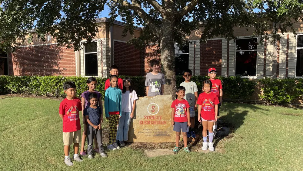 Pack 1103 scouts spray-painting a mustang stencil on the sidewalk at Stan C. Stanley Elementary