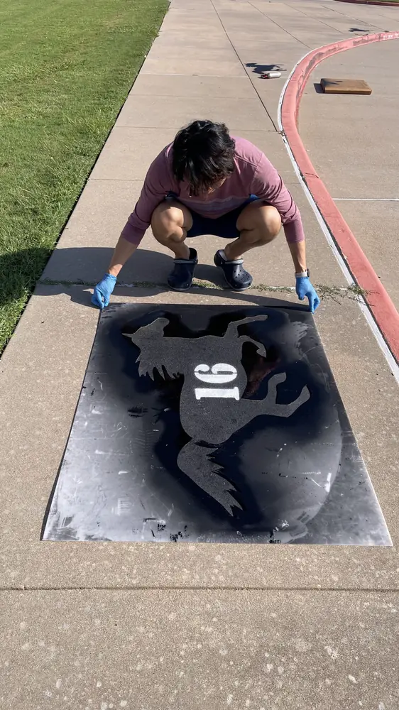 Lifting the stencil to reveal the painted mustang mascot